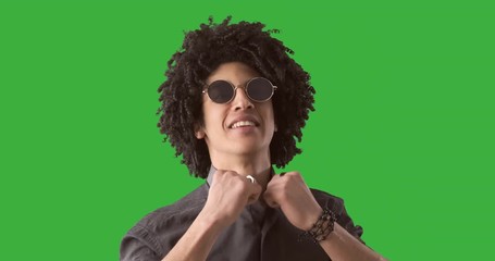 Handsome man posing with curly hair and sunglasses over green background