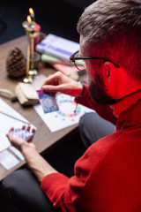 Bearded fortune-teller wearing red sweater reading divination cards