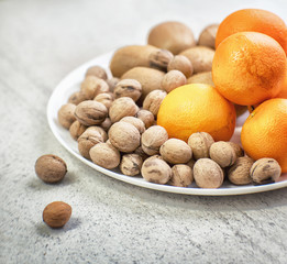 Walnuts, kiwi and oranges on a white plate