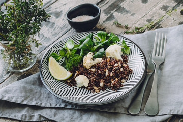 Roasted Cauliflower and Red Quinoa Salad with Pine Nuts on a wooden background, selective focus