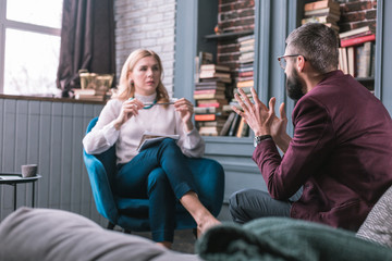 Bearded businessman wearing dark red jacket talking to private therapist