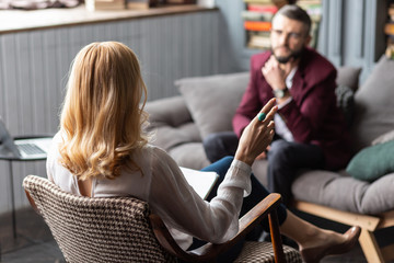 Blonde-haired therapist wearing blue ring talking to bearded man