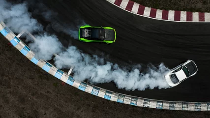 Selbstklebende Fototapeten Two cars drifting battle on race track with smoke, Aerial view two car drifting battle. © Kalyakan