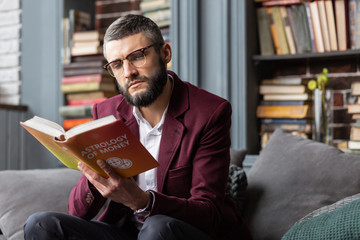 Man feeling thoughtful while reading book about astrology of money