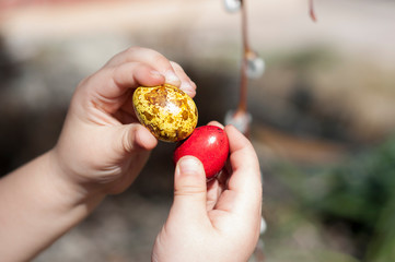 Red and yellow dyed quail eggs in children's hands