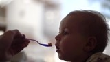Baby is fed with a spoon close up in slow motion