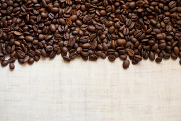 Black coffee grains lie on light wooden table, background image. place for text