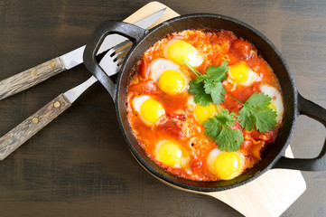 Shakshuka in the pan. Omelet with tomatoes, pepper, vegetables and herbs.