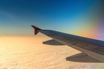 Fototapeta na wymiar Wing of airplane in with sunrise and blue sky.