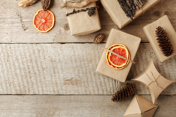Rustic gift wrapped in craft paper with natural decoration on wooden table with pine cones. Simple eco presents plastic free. Zero waste christmas concept, copy space