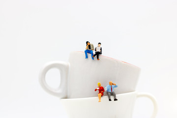 Miniature people: business team sitting on cup of coffee with morning news. Coffee time of business concept.