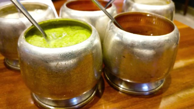 Panning up shot of various kinds of dosa chutney paste in silver holders