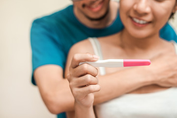 Obraz na płótnie Canvas Happy young couple asian woman and man smiling and holding pregnancy test, Wellness and healthy concept, Abortion problem, Selective focus.