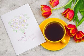 beautiful tulips ,cup of drink and handmade card with kid's drawing  for Mother's Day on marble background, top view
