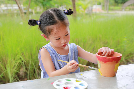 Asian kid girl paint on earthenware dish.