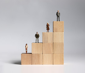Wooden blocks and miniature people. The concept of gender discrimination in a company.