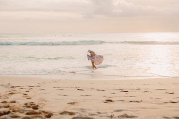 Attractive woman in summer dress on ocean beach at sunset.