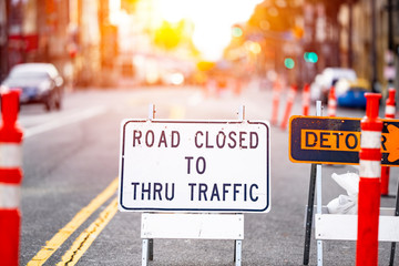 Road closed and detour sign in a road construction site work zone in the middle of a blocked street and traffic - Powered by Adobe