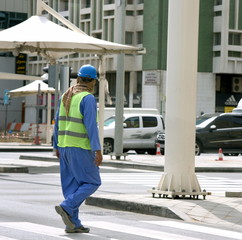 Arbeiter mit Helm und Sonnenschutz im Straßenverkehr von Abu Dhabi
