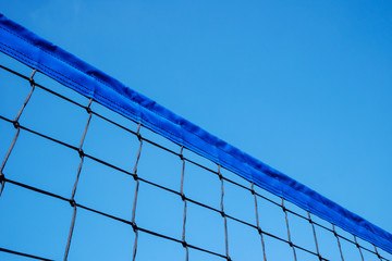 Fragment of volleyball net against clear blue sky background. Copy space