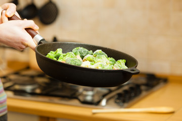 Woman cooking stir fry frozen vegetable on pan
