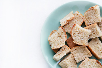 delicious croutons of bread on a plate top view and white background for text