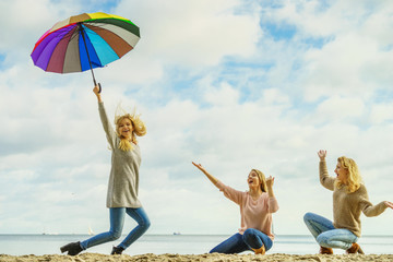 Women holding umbrella having fun with friends