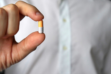 Doctor holding pill, male hand with medication in capsule close-up. Man with tablet, concept of...