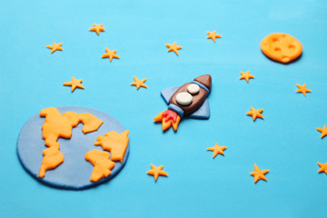 Creative craft plasticine rocket in open space, astronaut dreams. Stars, planet earth and moon. Cartoon art.
