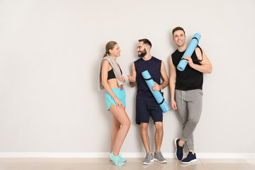 Fototapeta premium Sporty young people near light wall