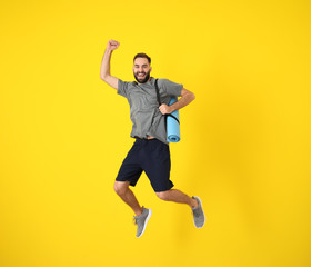 Young sporty man jumping against color background