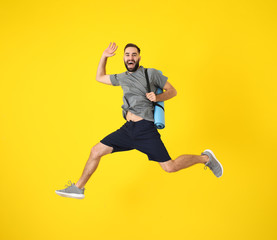 Young sporty man jumping against color background