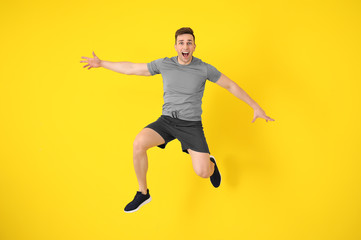 Fototapeta na wymiar Young sporty man jumping against color background