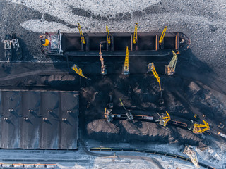 Loading coal mining in port on cargo tanker ship with crane bucket of train. Aerial top view