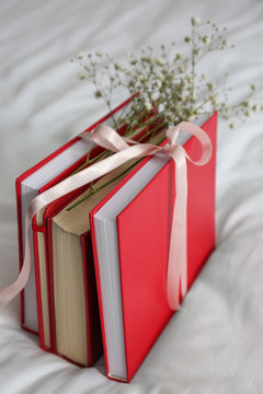 Books Tied With Ribbon And Flowers On Bed