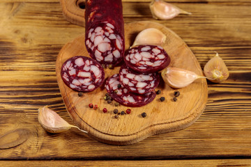 Sliced salami sausage on cutting board on wooden table