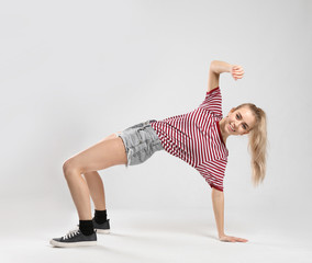 Young female dancer on light background