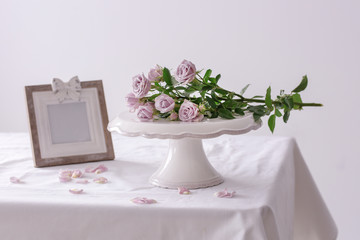 Dessert stand with fresh rose flowers on table against light background