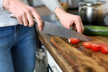 Beautiful woman cutting vegetables in kitchen at home, closeup