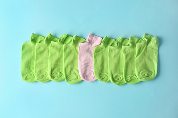 Pink sock among green ones on color background. Concept of uniqueness