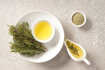 Oil with fresh and dry rosemary on grey table