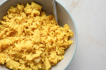 Bowl with tasty rice, corn and nuts on light table