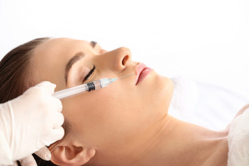 Young woman receiving filler injection in beauty salon