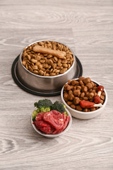 Bowls with dry and fresh pet food on floor
