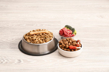 Bowls with dry and fresh pet food on floor