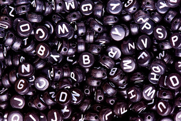 Black beads with white English letters close-up.