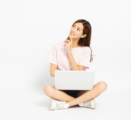Happy young woman sitting on the floor using laptop