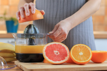 Woman's hands is holding a grapefruit half and making juice