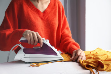 Young woman ironing clothes at home