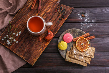 Cup of hot tea with sweets on wooden table